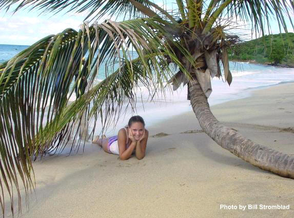 Cane Bay Beach, St. Croix with a girl laying in the sand under a Palm tree.