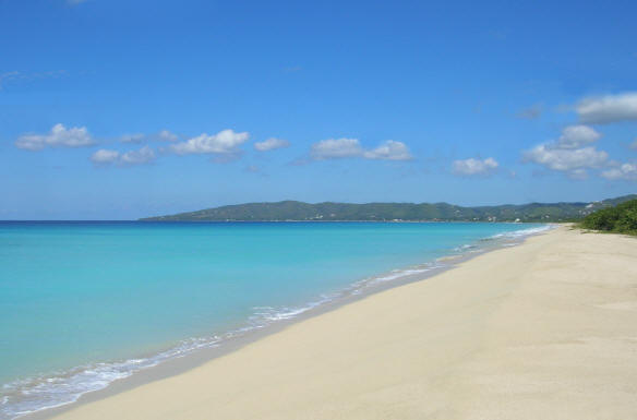 A view of the beach in the Sandy Point National Wildlife Refuge and Beach on St. Croix, USVI. The sand is soft and white, and the water is turqouise and clear.